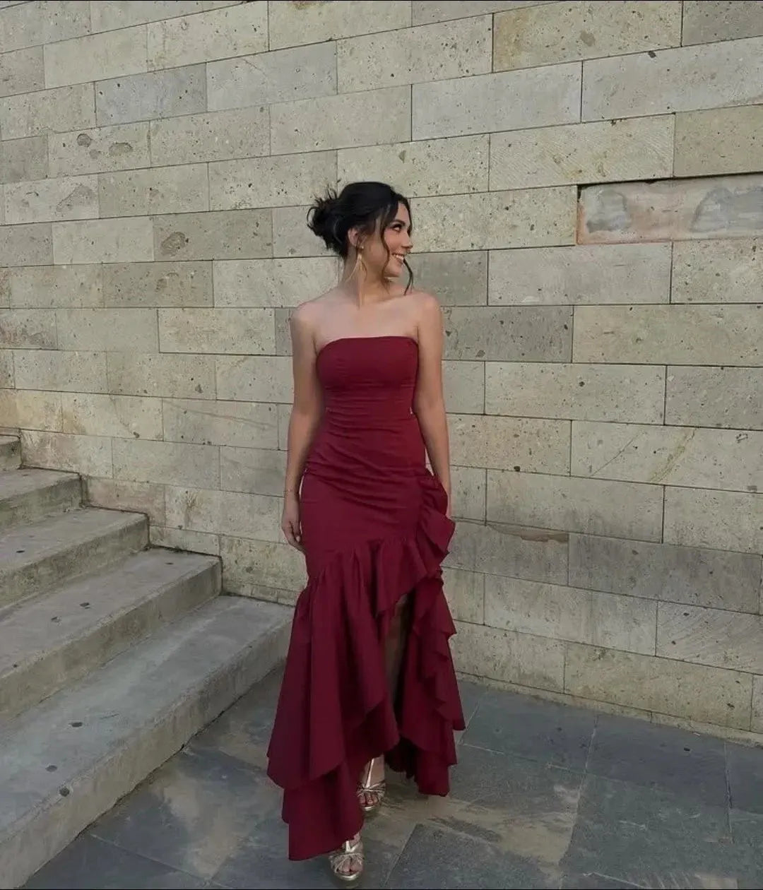 Burgundy mermaid strapless sweetheart dress with ruffle slit and floor-length hem.