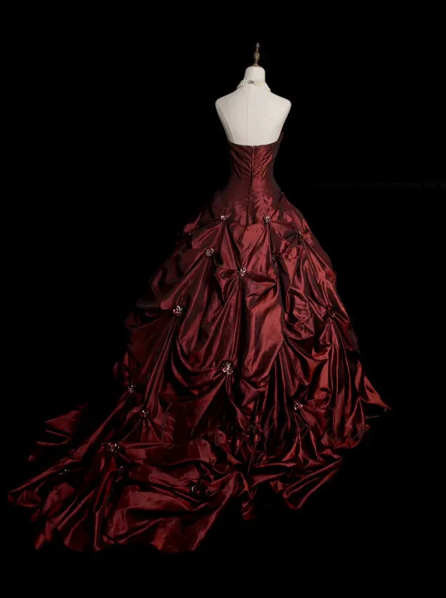 Back view of a model in a burgundy strapless formal gown with a ruched skirt.
