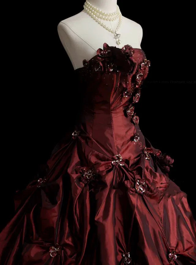 Side view of a model showcasing the burgundy strapless ball gown's silhouette.