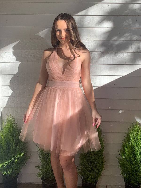 Model wearing a blush pink A-line halter mini dress with ruffles.