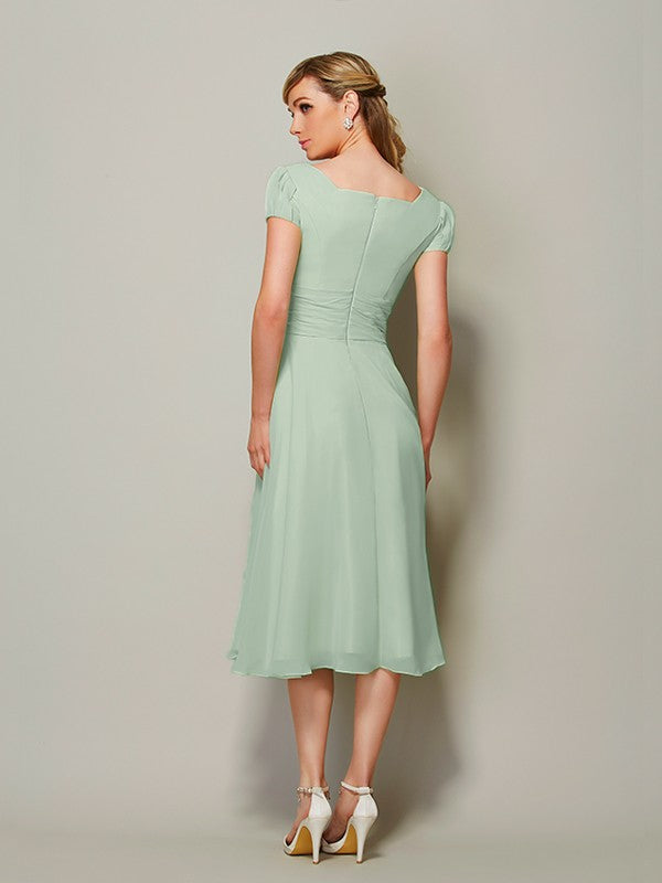 Elegant tea-length bridesmaid dress with bateau neckline and ruffles.