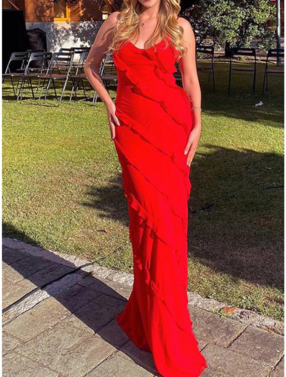 Woman wearing a black sleeveless maxi dress with spaghetti straps and ruffle detail.