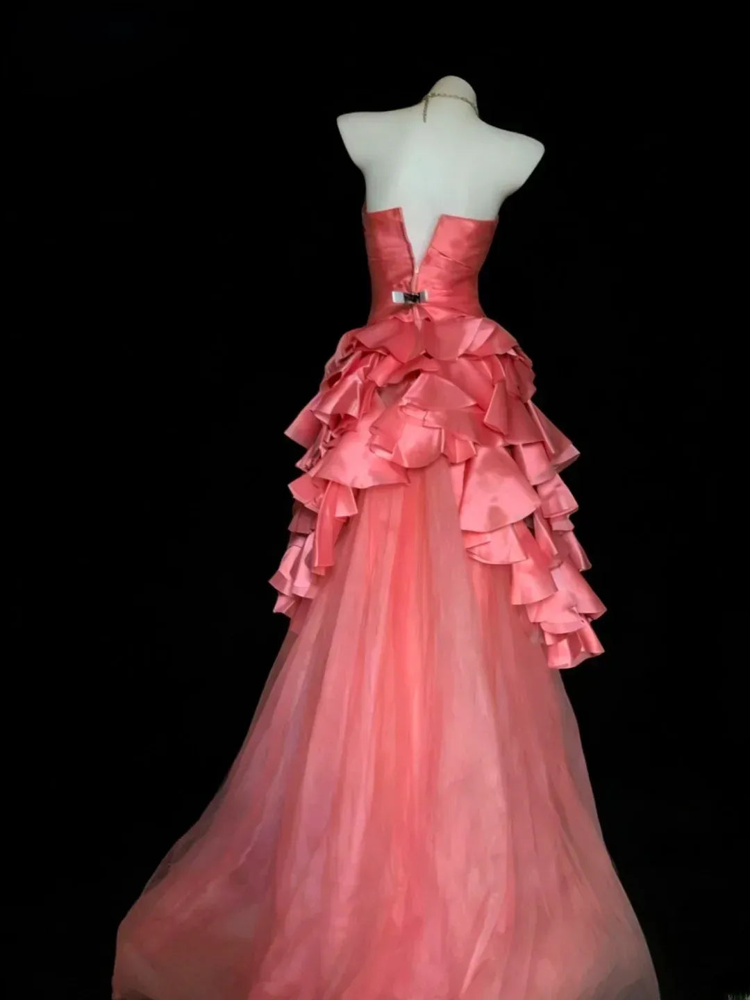 Side view of the coral pink strapless ball gown, highlighting the flowing tulle skirt and subtle court train.