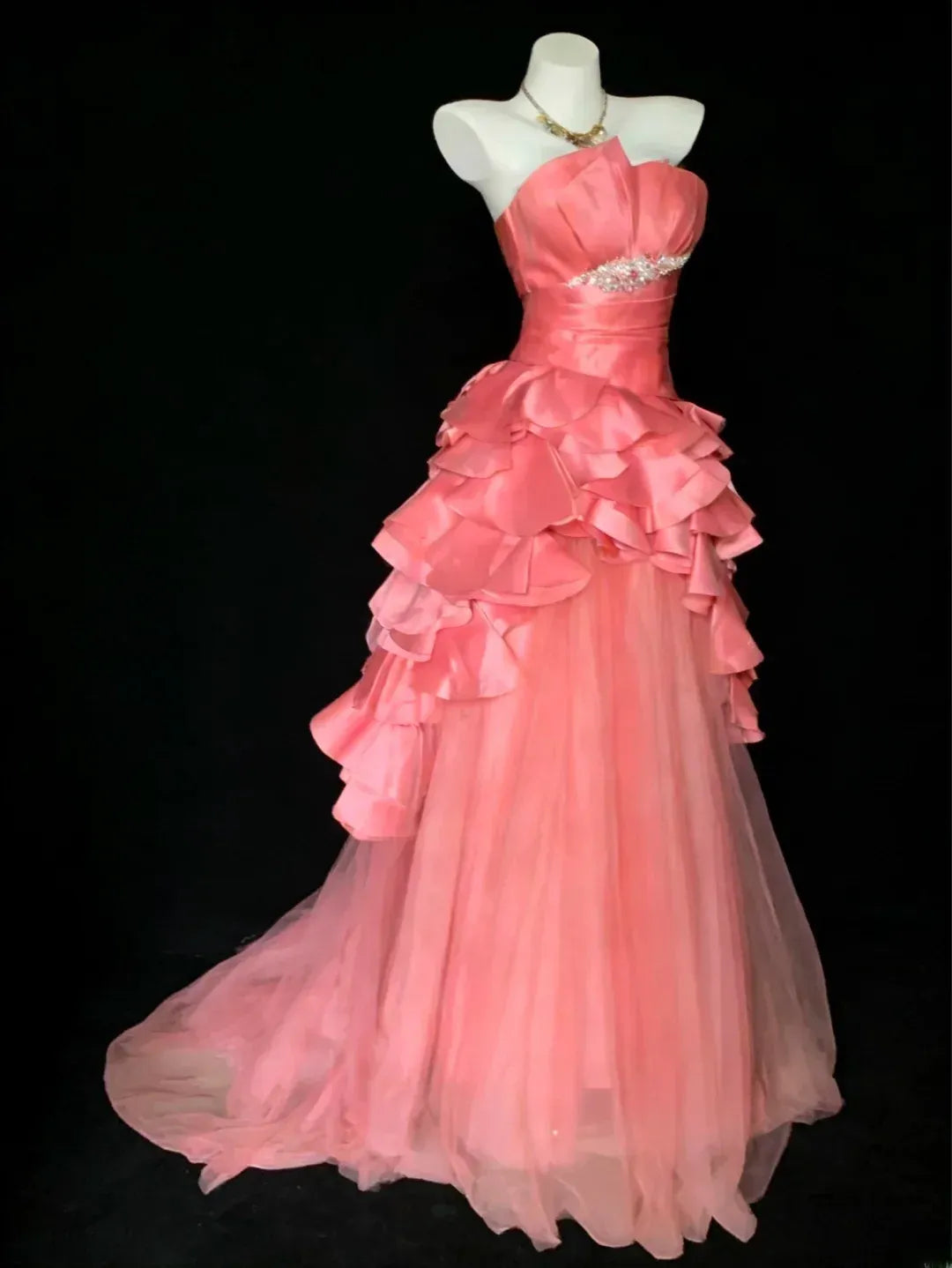 Back view of the coral pink strapless ball gown, showing the zip closure and elegant court train.
