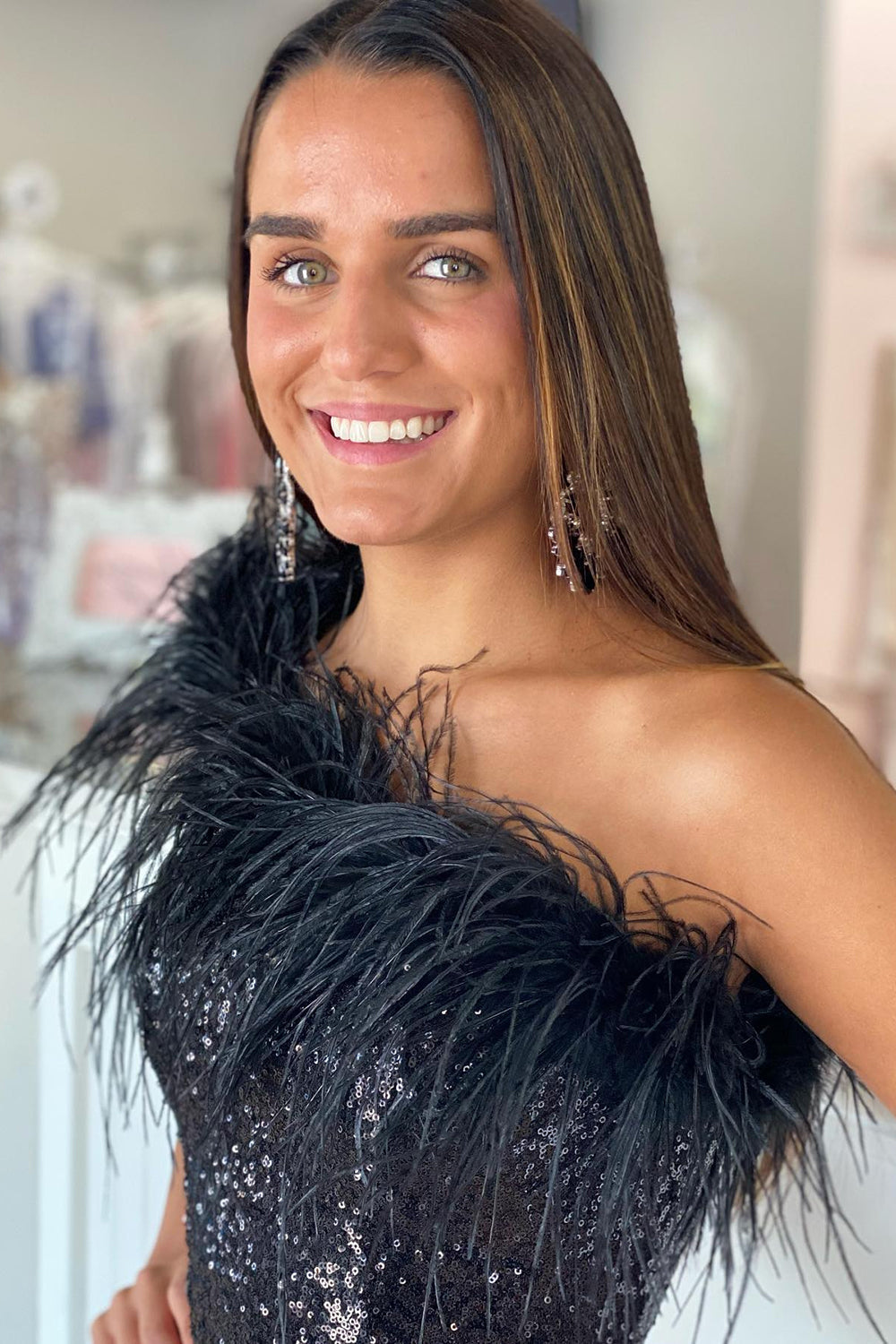 Model wearing a black bodycon sequin mini dress with feather trim, side view.