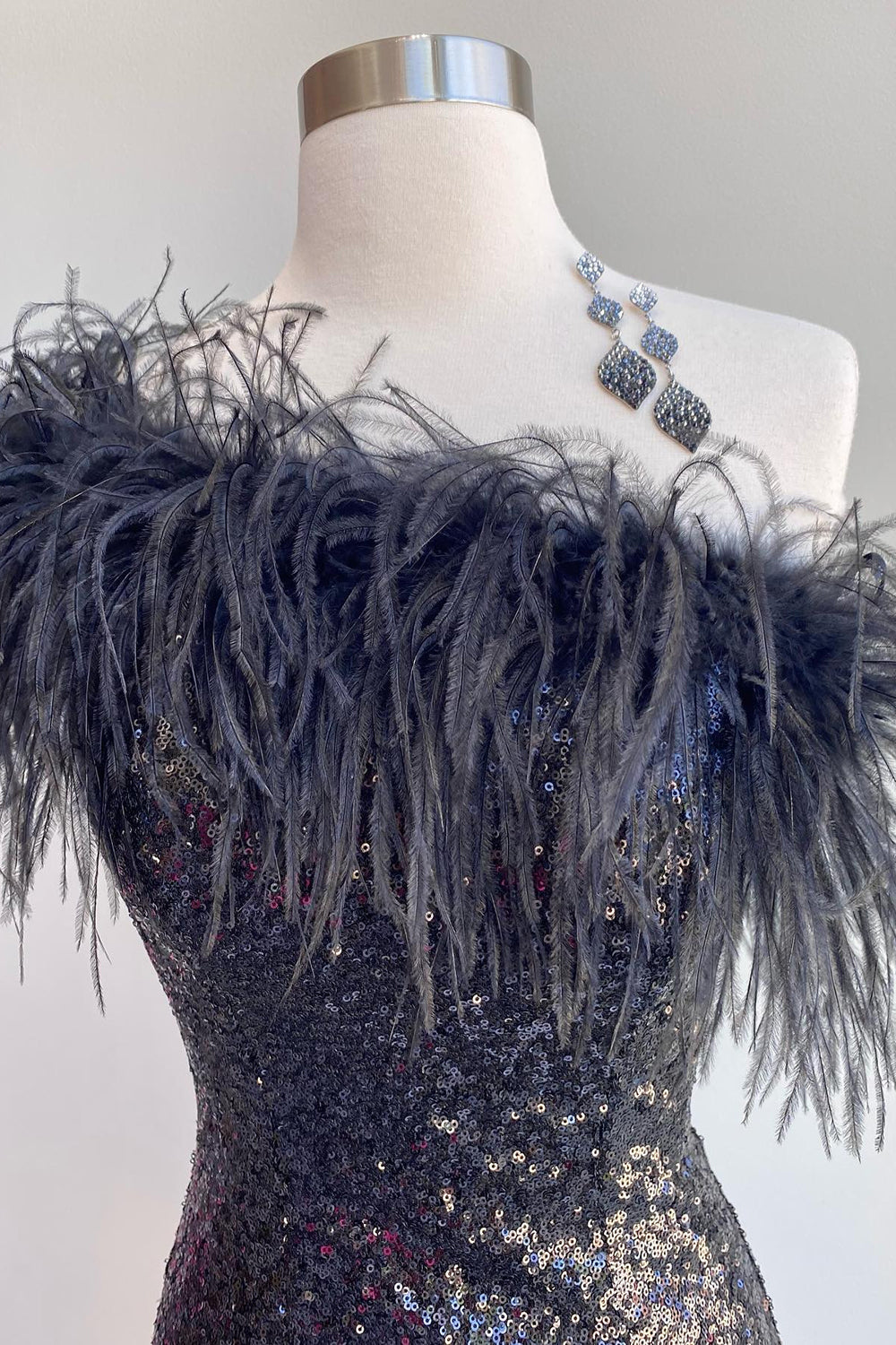 Close-up of the sequin and feather details on a black bodycon dress.