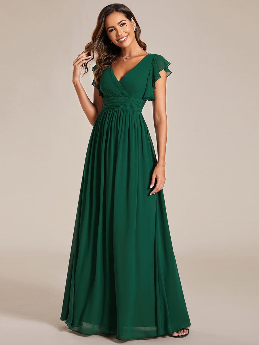 Model wearing a dark green A-line chiffon bridesmaid dress with a back cutout and ruffle sleeves.