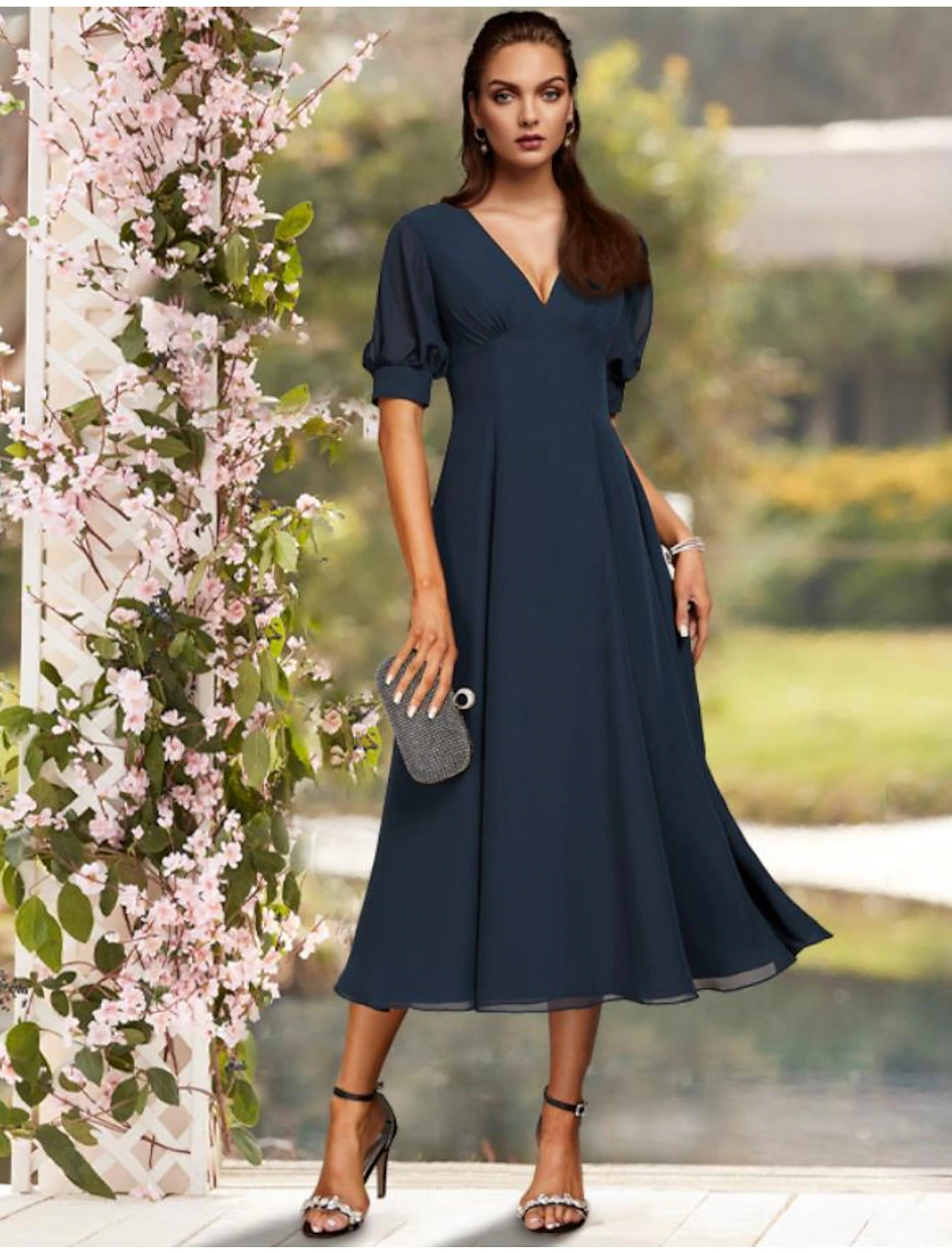 Woman wearing an elegant A-line jewel neck short sleeve tea length chiffon dress.