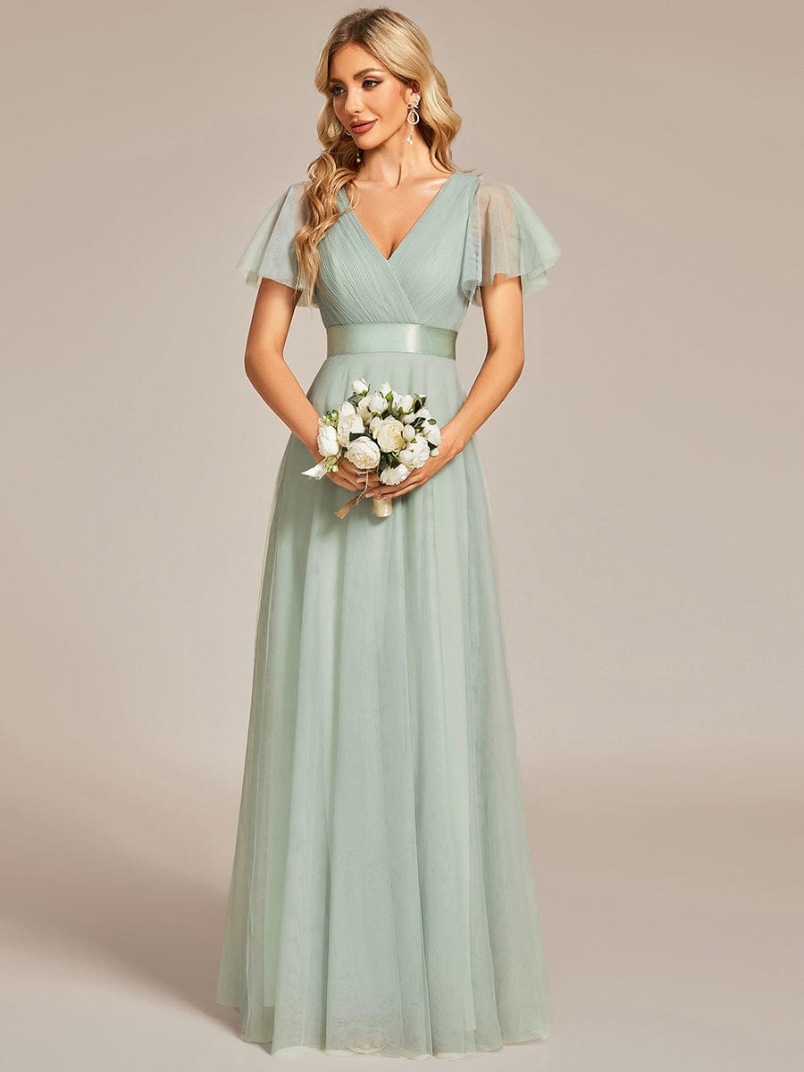 Woman posing in a green double V-neck tulle bridesmaid dress.