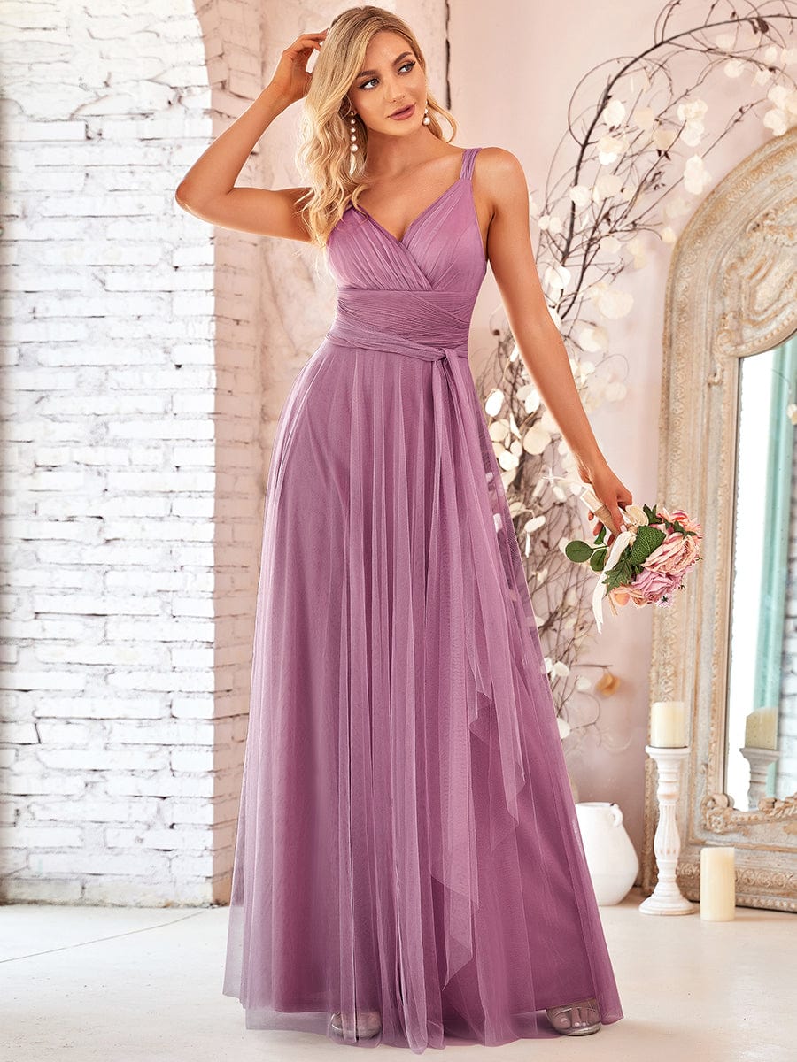 Model in a dark floor-length double V-neck tulle bridesmaid dress, side view.
