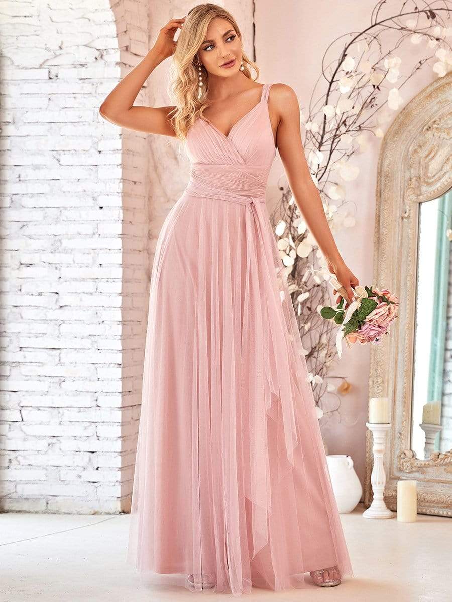 Back view of a model in a light pink double V-neck tulle bridesmaid dress.