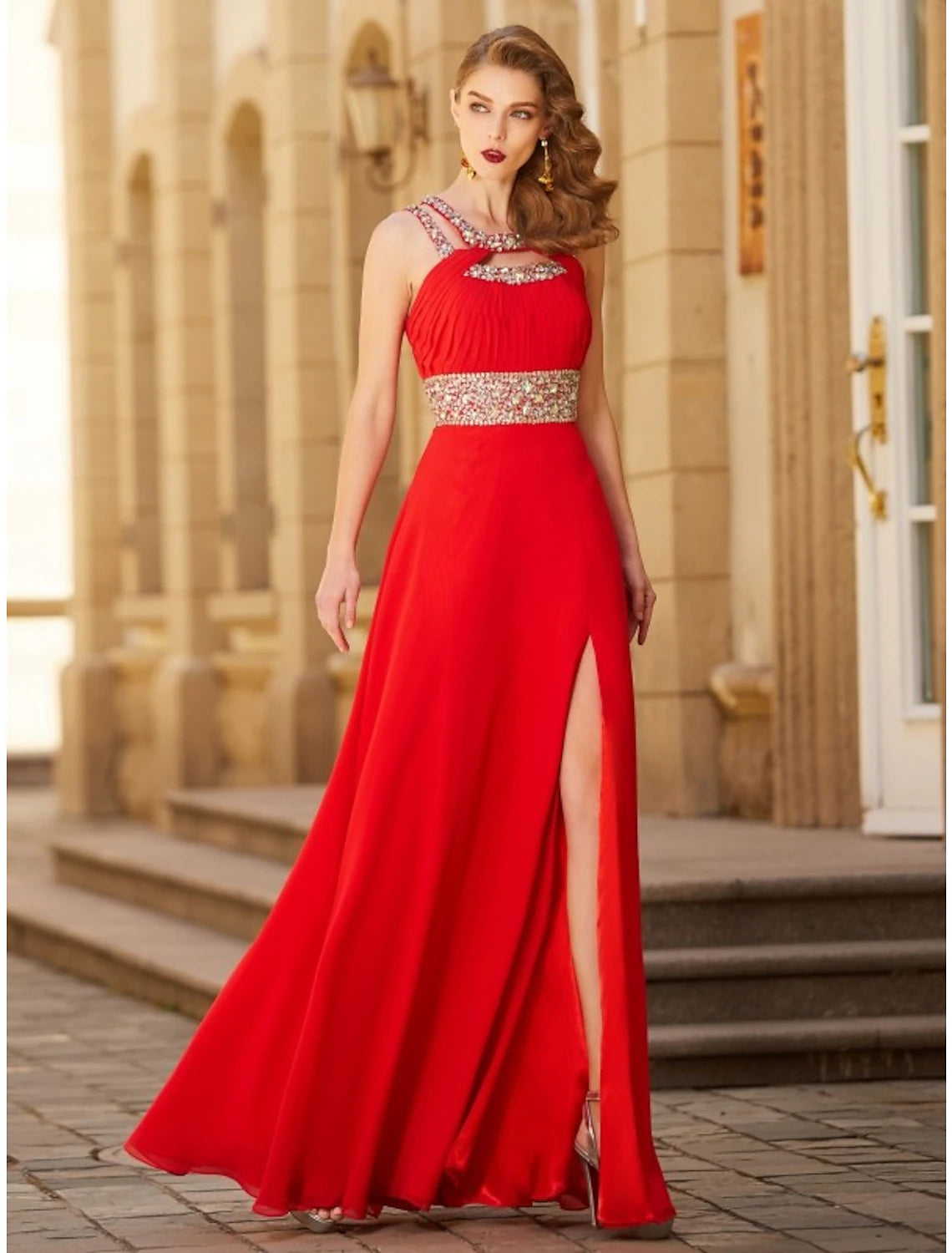 Model wearing a dark A-line halter neck evening gown with a rhinestone slit, posing elegantly.