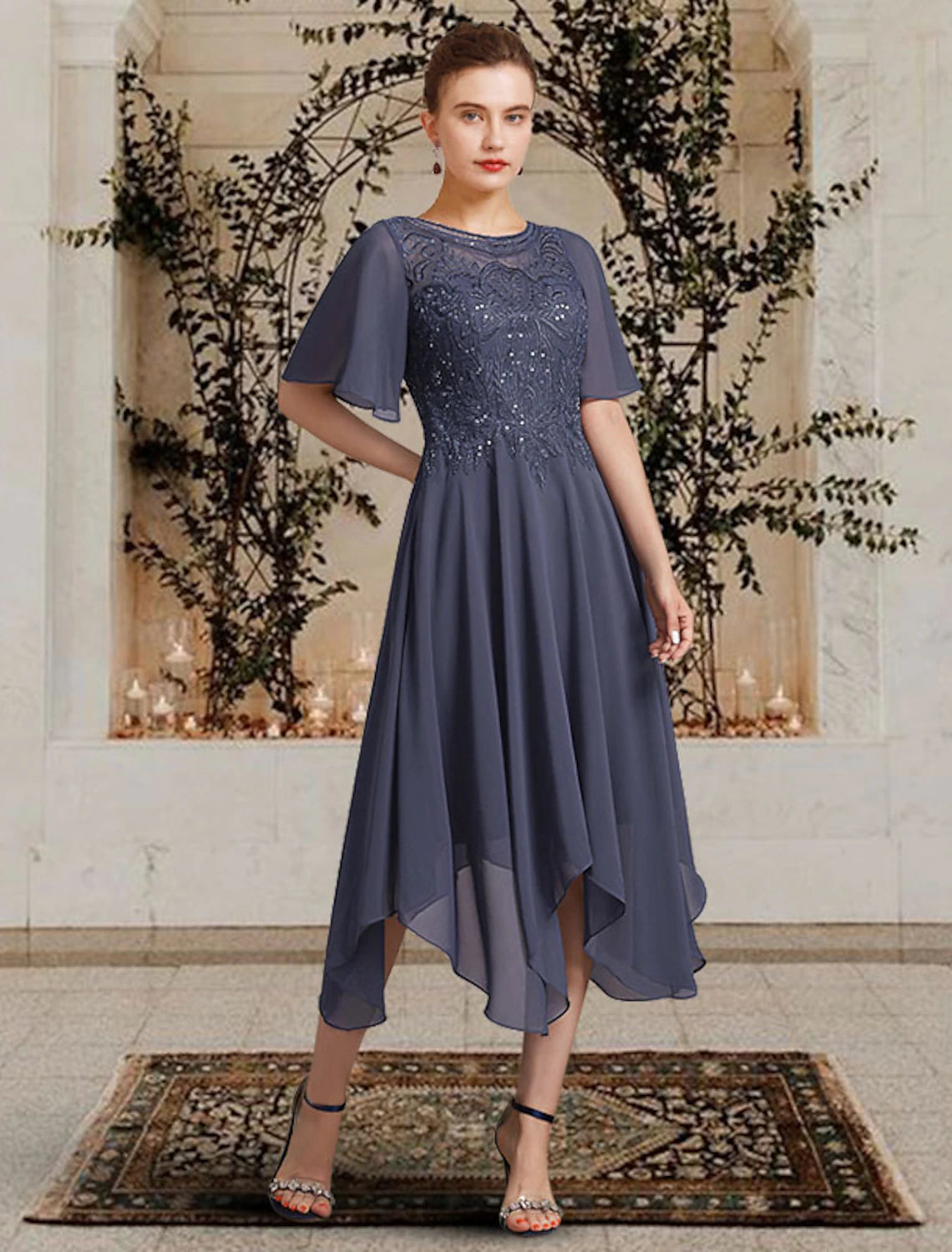 Woman wearing an elegant A-line mother of the bride dress with jewel neck and short sleeves.