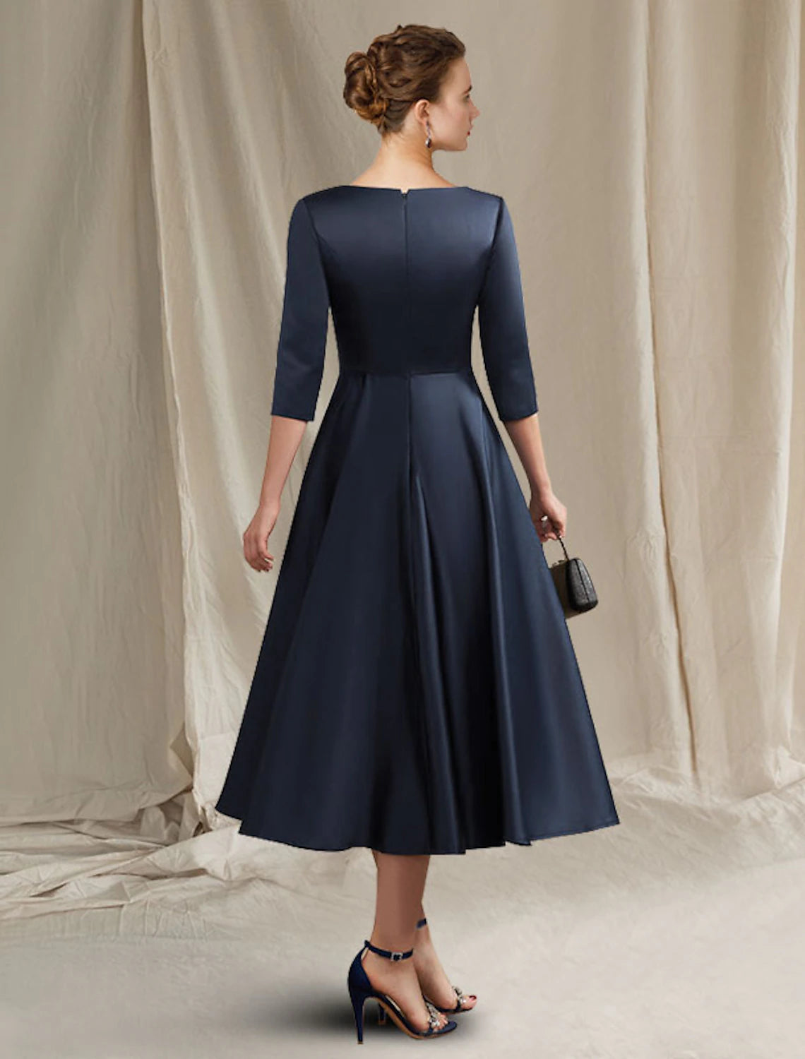Side view of the tea-length satin Mother of the Bride dress, showing pleats and half sleeves.