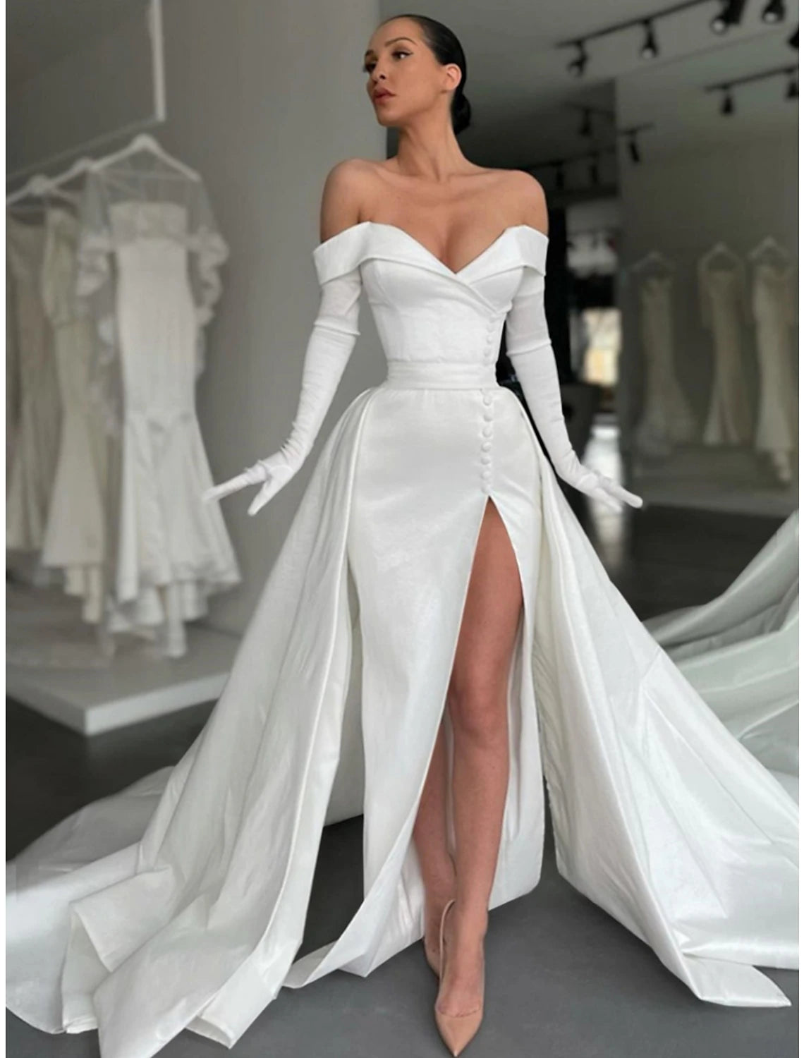 Woman wearing an elegant black A-line off-shoulder satin evening gown with a court train and thigh-high slit.