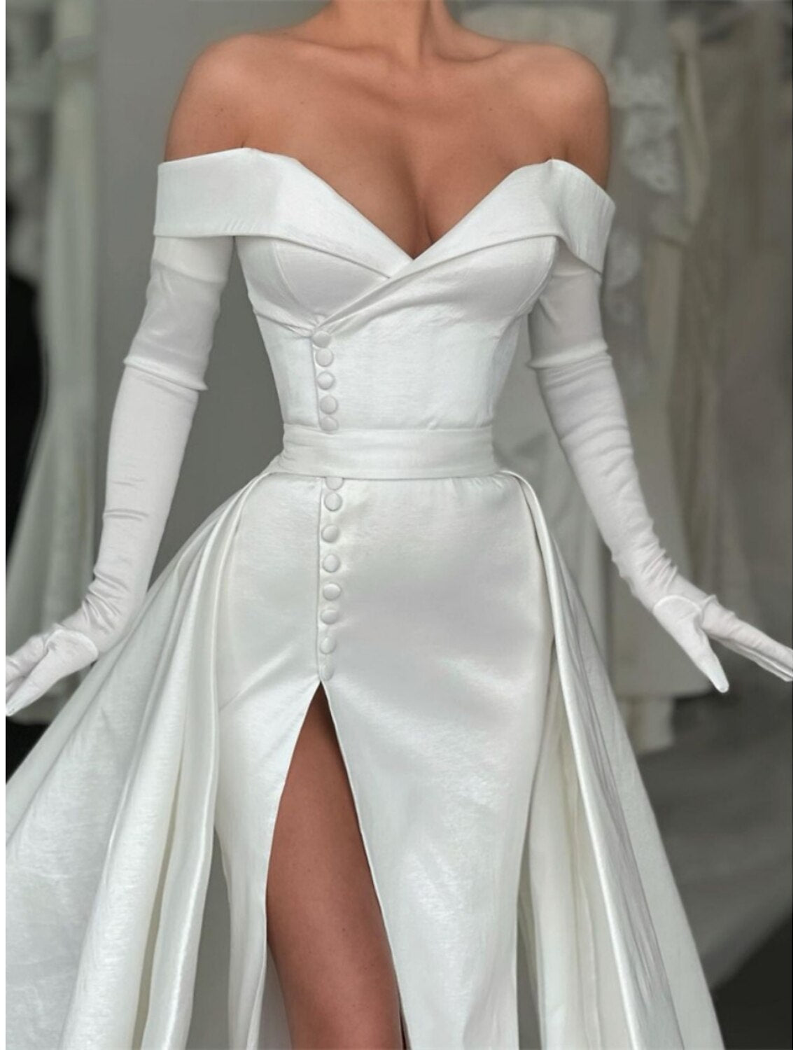 Close-up of the off-shoulder neckline and long sleeve of the elegant black satin evening gown.