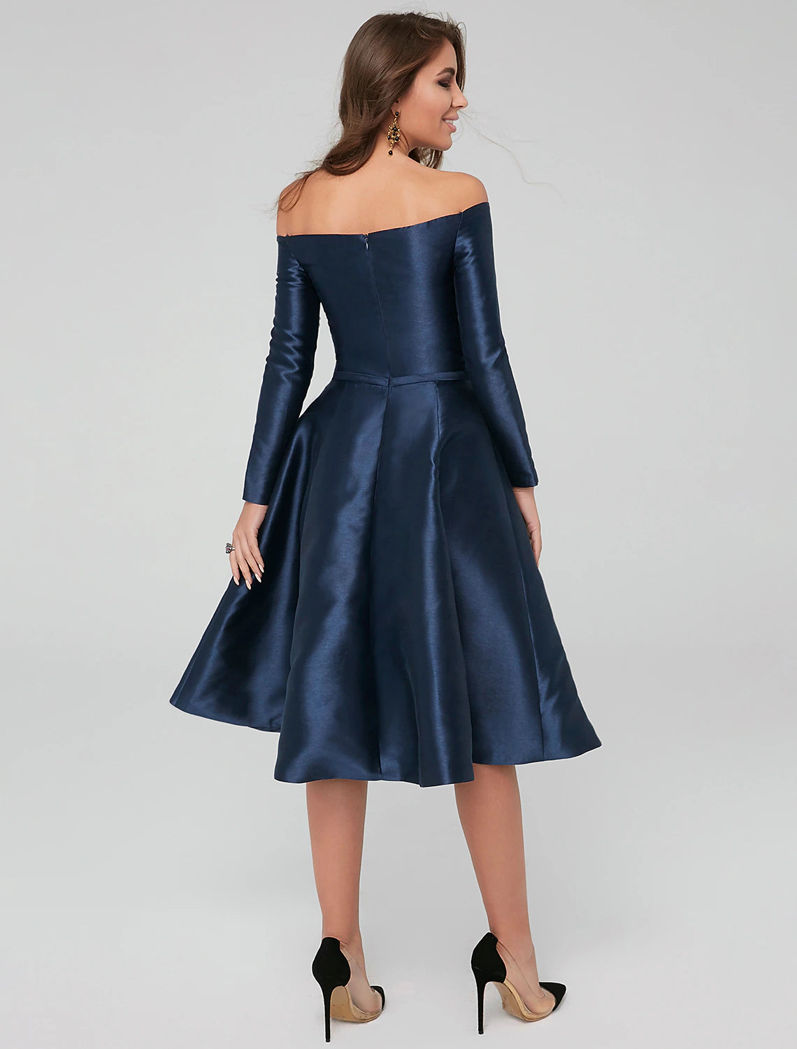 Woman posing in a knee-length satin cocktail dress with pleats.