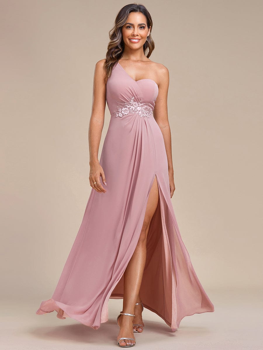 Model wearing a red A-line one-shoulder bridesmaid dress with waist applique and high slit.