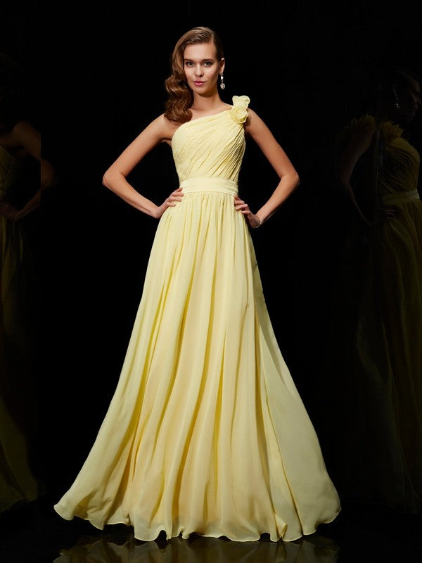 Woman wearing a long one-shoulder A-line chiffon bridesmaid dress with flower detail.