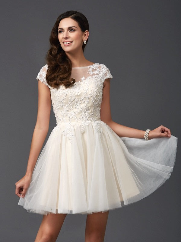 Light-colored A-line princess dress with scoop neck and short sleeves, featuring floral appliques.