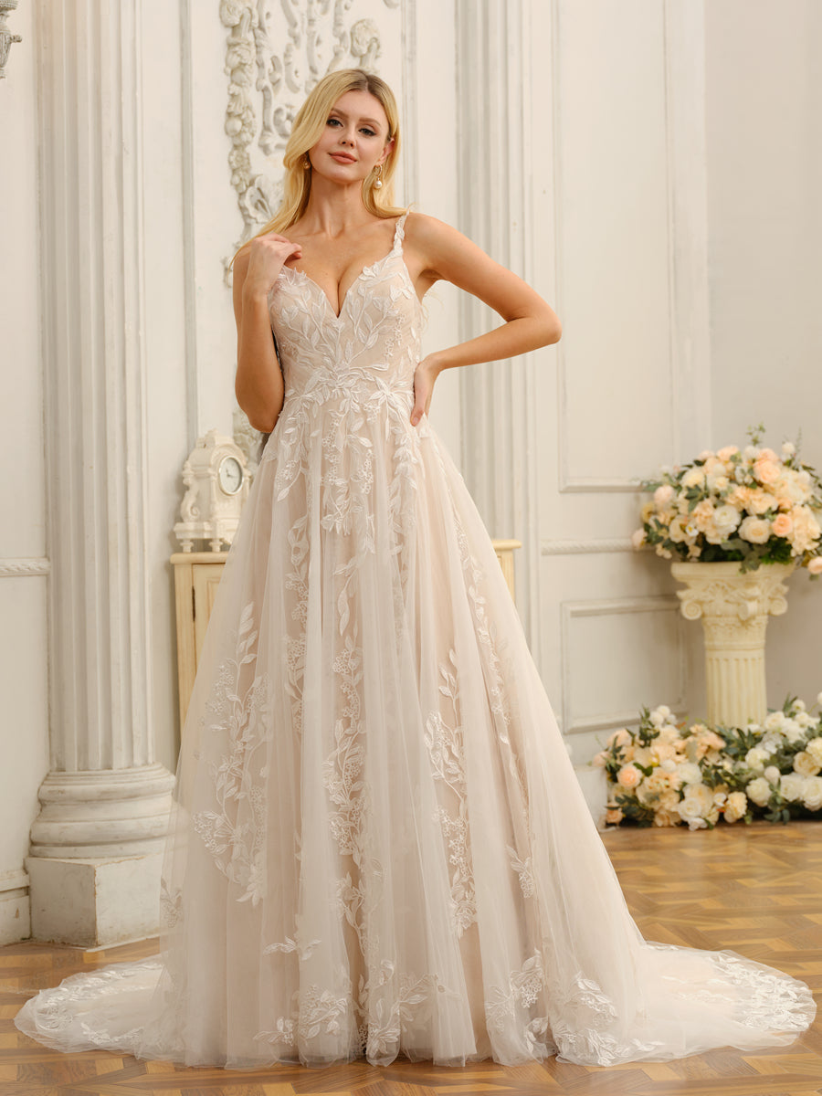 Bride in a white A-line princess wedding dress with spaghetti straps and intricate appliques.