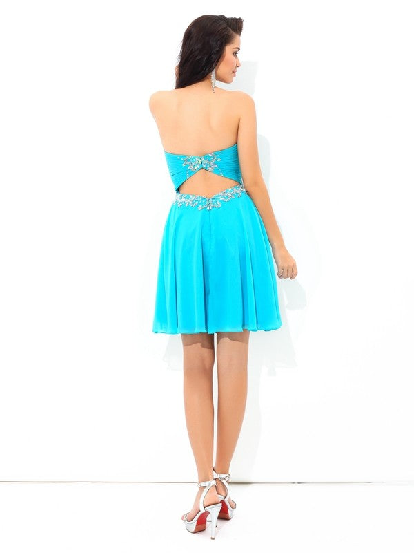 Side view of a woman in a short chiffon cocktail dress with pleats.