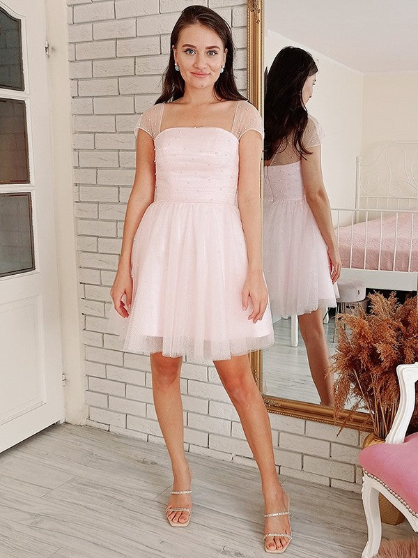Model wearing an elegant A-line tulle beaded strapless mini cocktail dress.