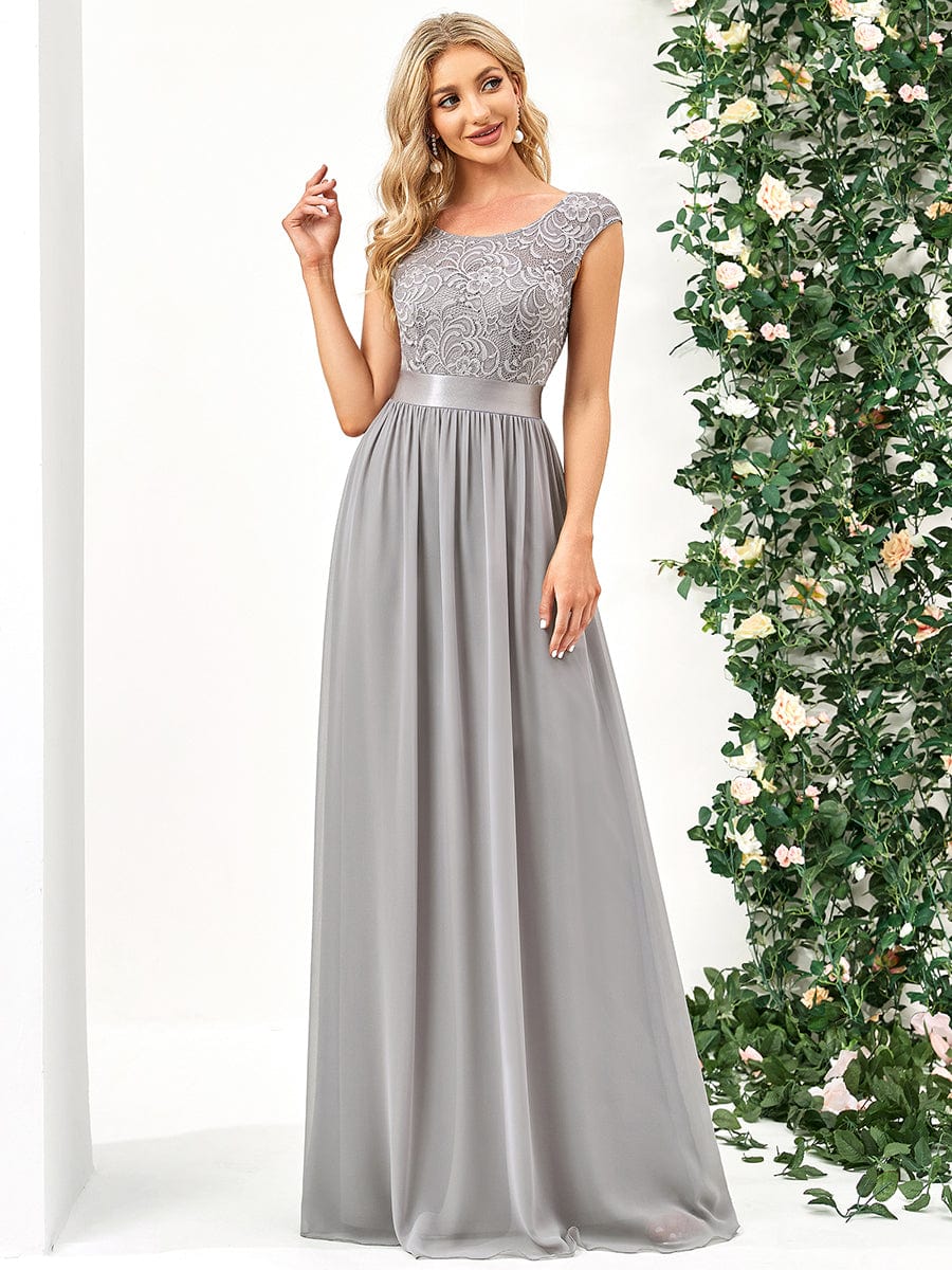 Model in a grey A-line bridesmaid dress with a round neck and lace bodice.