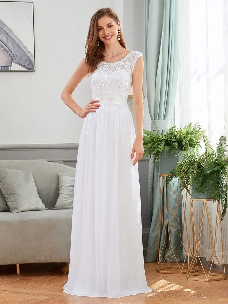Model in a white A-line bridesmaid dress with a round neck and lace bodice.
