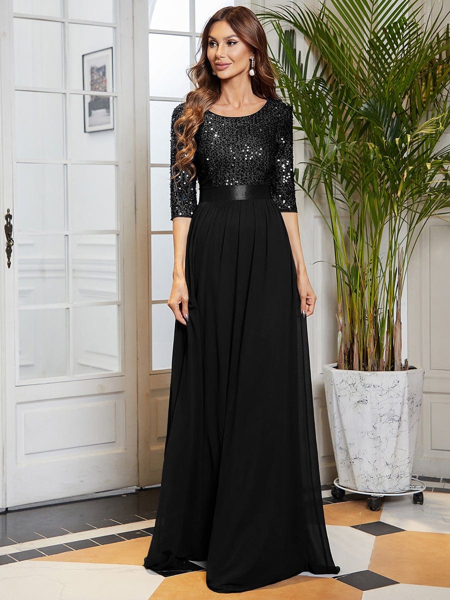 Woman in a black long sleeve sequin evening dress with a round neckline.