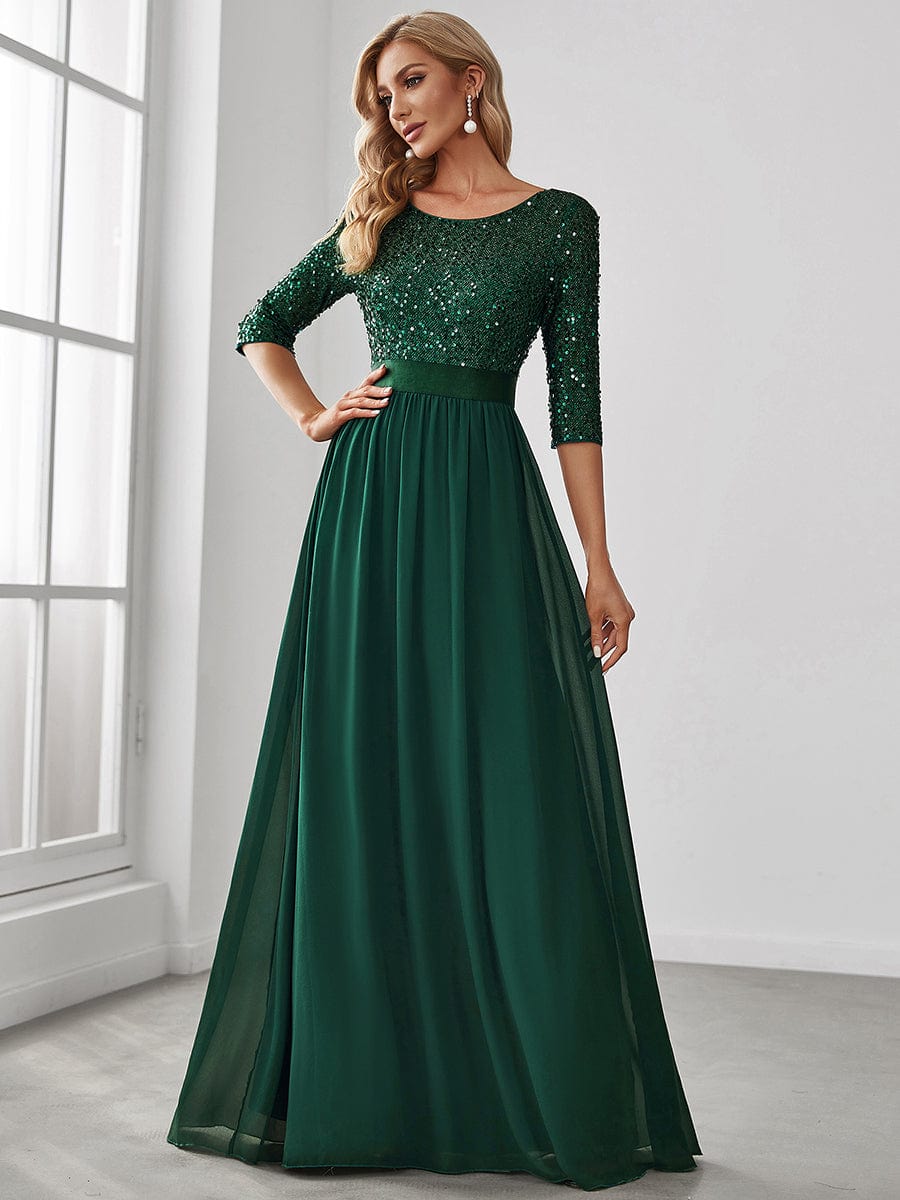 Woman in a dark green long sleeve sequin evening dress.