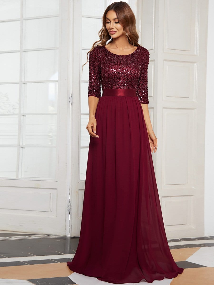 Woman in a burgundy long sleeve sequin evening dress.