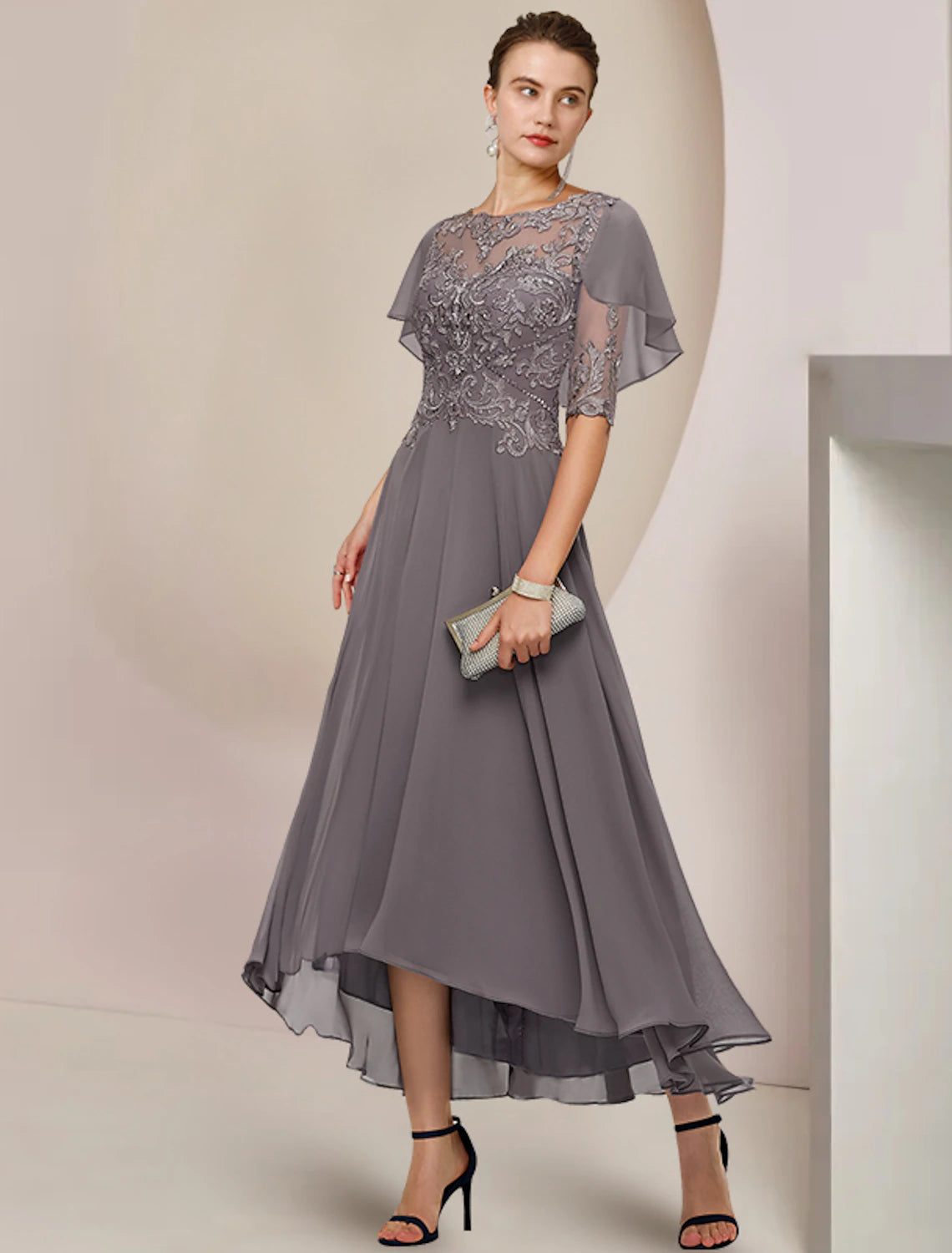 Woman wearing an elegant A-line scoop neck tea length mother of the bride dress with half sleeves and lace details.