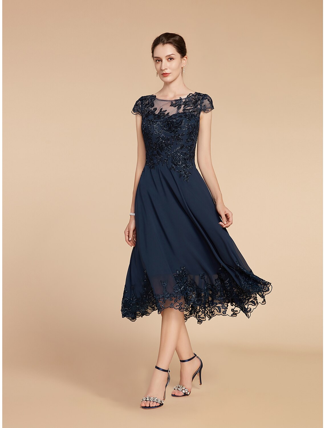 Model wearing an elegant A-line scoop neck tea length lace dress with 3/4 sleeves and sequin appliques.