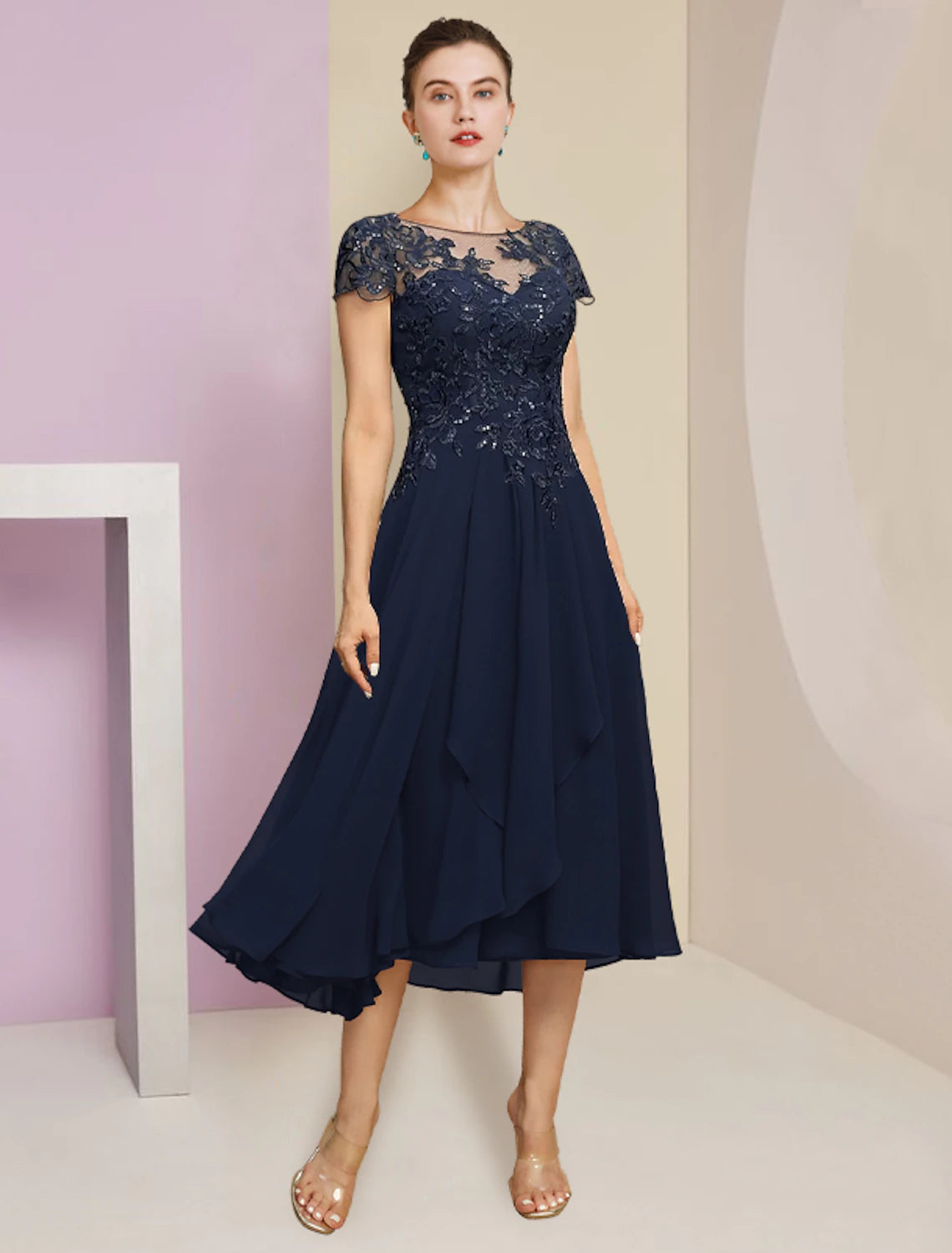 A woman posing in the elegant tea-length mother of the bride dress.