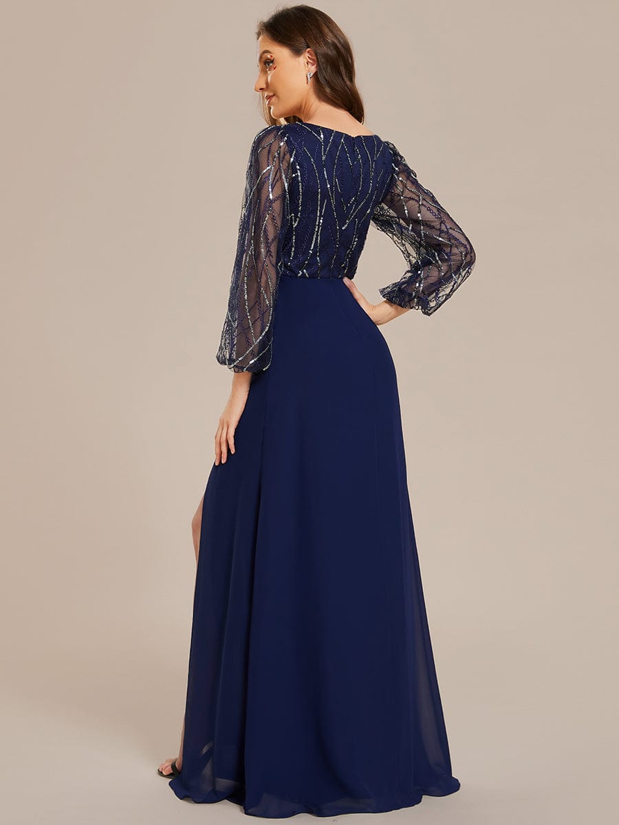 Model wearing a navy blue sequin and chiffon A-line evening dress with long sleeves and a high slit, side view.
