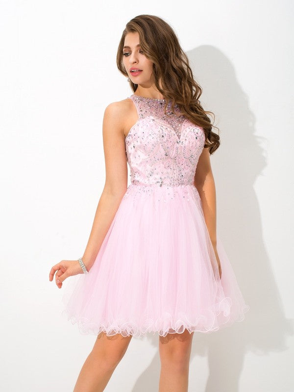Woman wearing a short A-line cocktail dress with sheer beaded neckline.