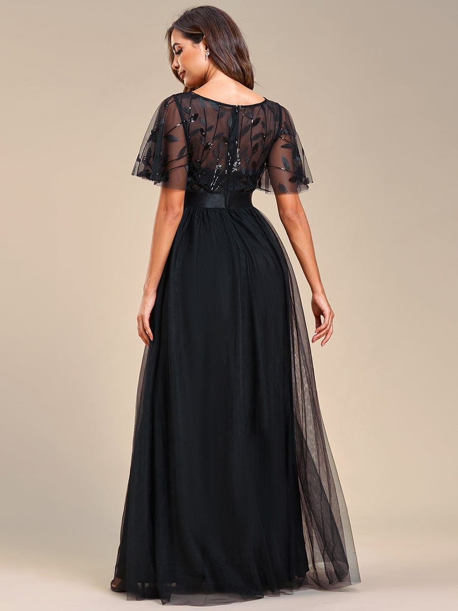 Back view of a woman in a black A-line short sleeve embroidered evening gown, showcasing the intricate details.