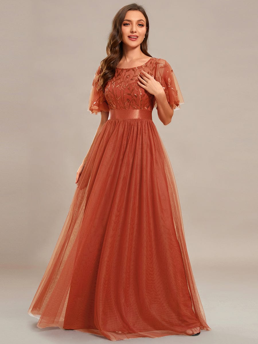 Woman wearing a burgundy A-line short sleeve embroidered floor length evening gown.