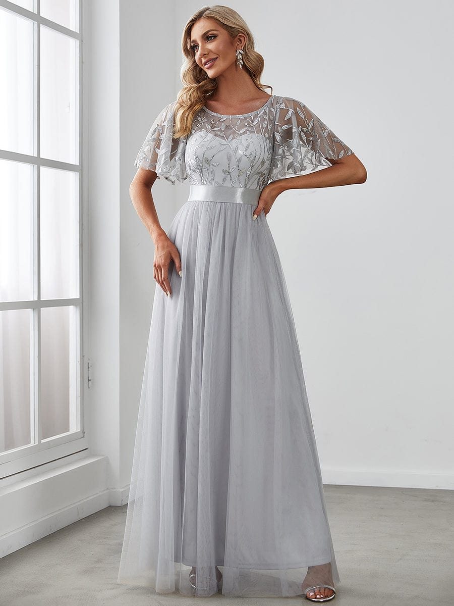 Woman wearing a grey A-line short sleeve embroidered floor length evening gown.