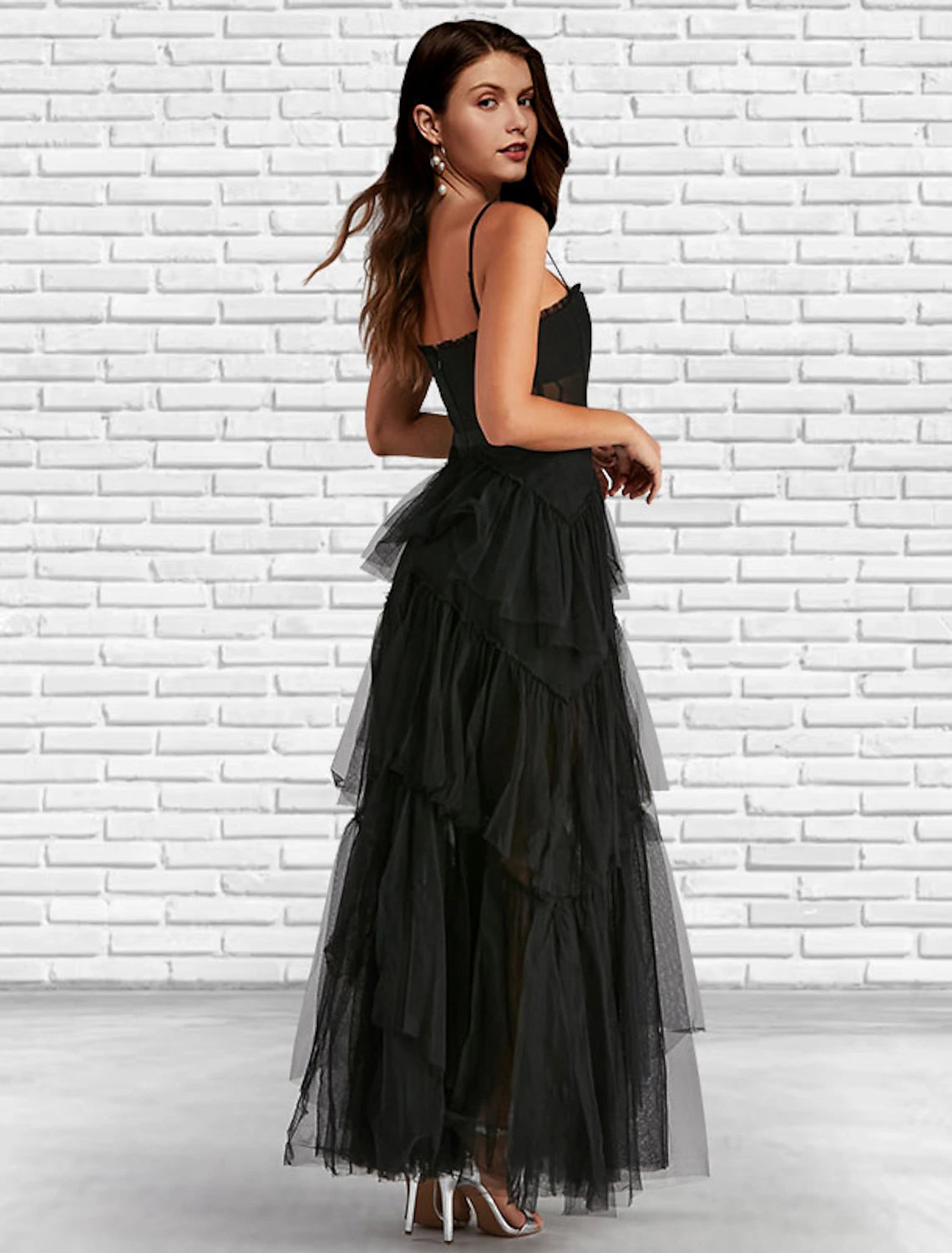 Back view of a model in a ruffled A-line prom dress, showcasing the ladder back detail.