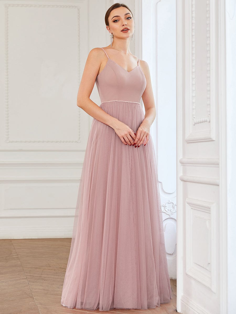 Close-up of the sweetheart neckline and delicate spaghetti straps on a red tulle dress.