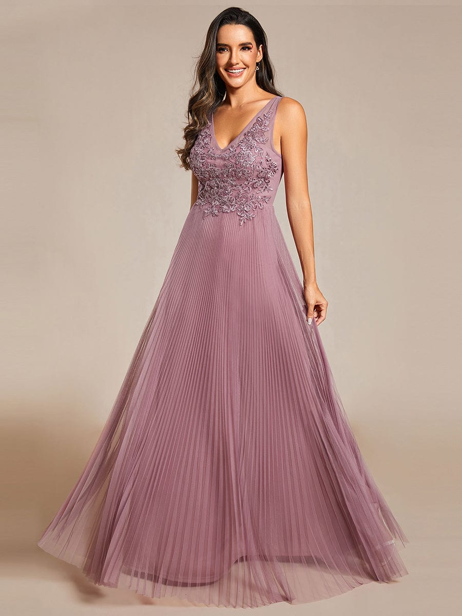 Model wearing a red A-line tulle evening dress with intricate applique embroidery bodice.