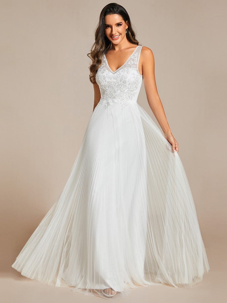 Model wearing a cream A-line tulle evening dress with applique details.