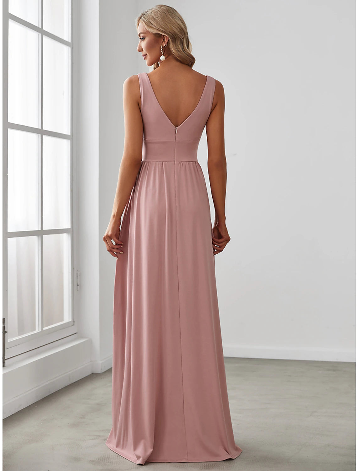 Back view of a woman in a flowing A-line V-neck chiffon gown.