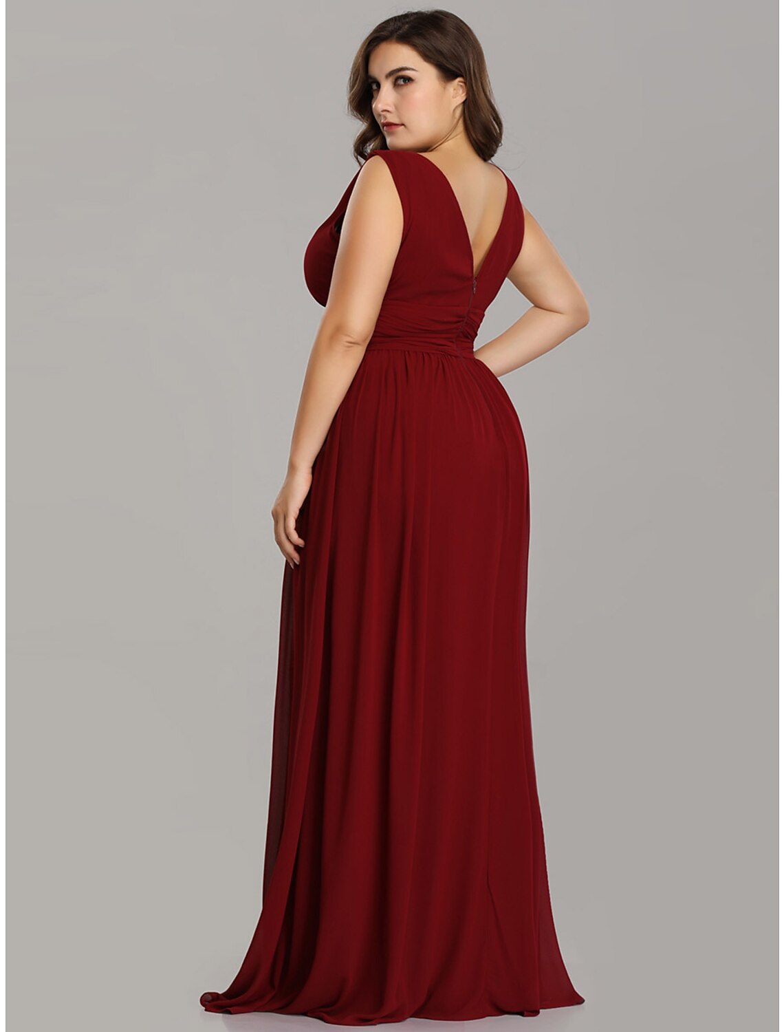 Model in a dark A-line V-neck pleated chiffon gown, showing the V-back.