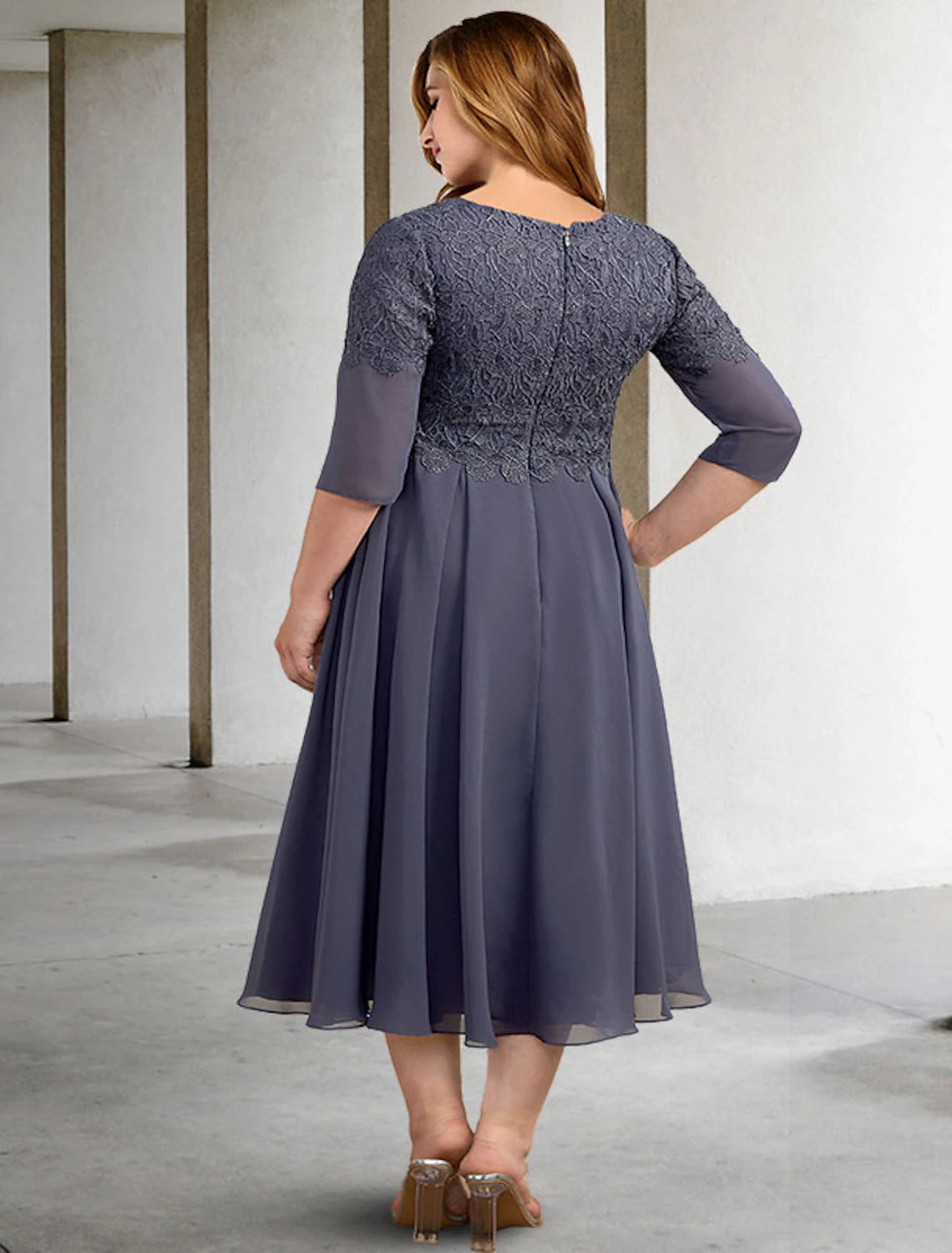 Back view of the A-line chiffon dress with button details worn by a woman.