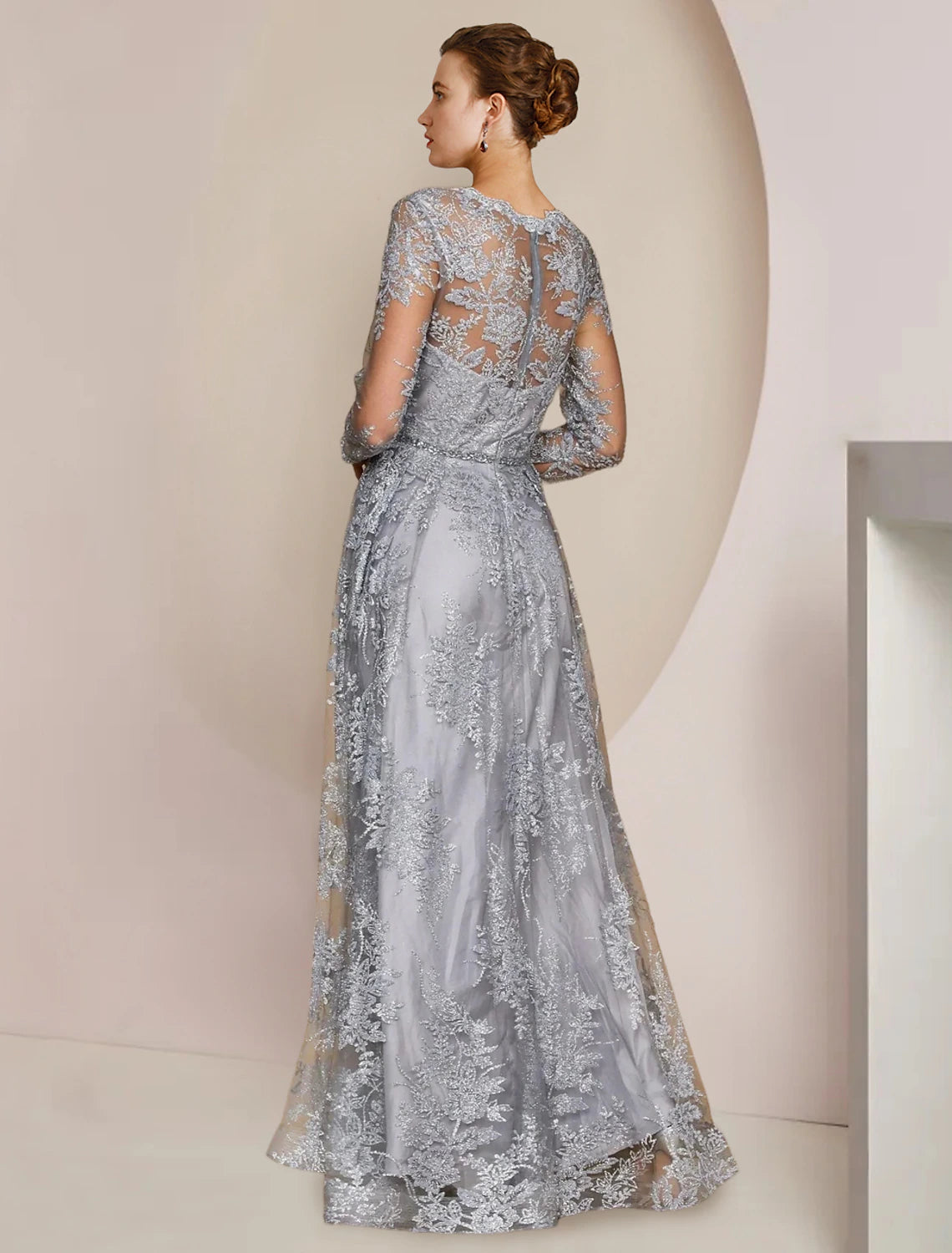 Woman posing in a sophisticated A-line lace gown with long sleeves and V-neck.