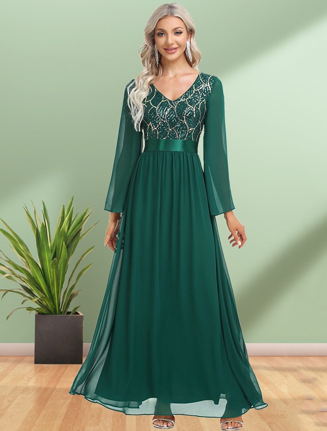 Model wearing a dark, sequined A-line evening gown with long sleeves and a V-neck.