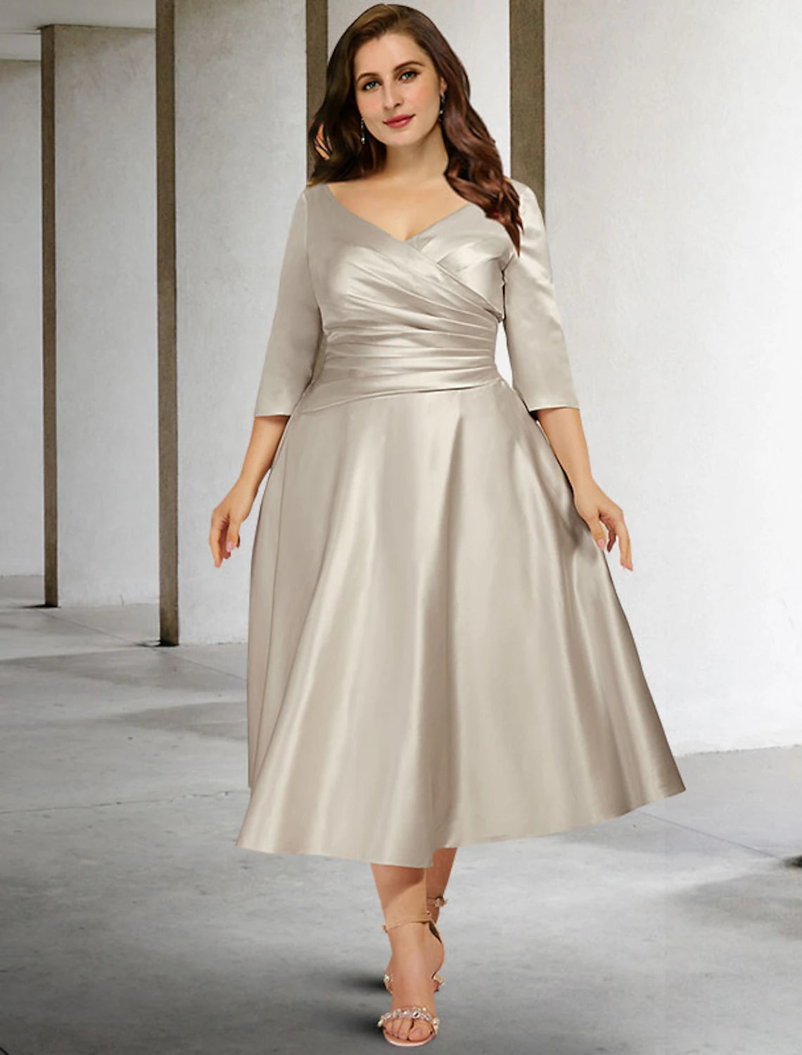 Woman wearing a dark A-line V-neck ruched satin tea-length dress.